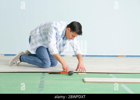 Carpenter installing laminate flooring in room Stock Photo