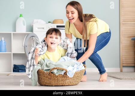 Young woman with her little son having fun while doing laundry at home Stock Photo