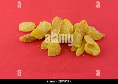 Crystallized ginger pieces snack with sugar coating on red background Stock Photo