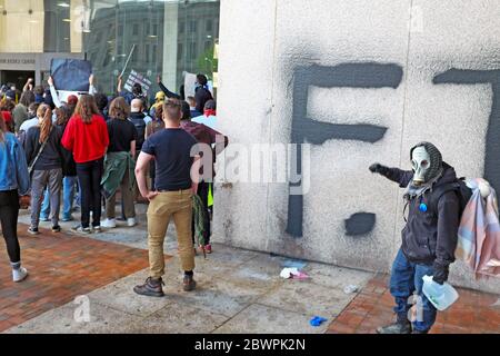 A protester stands in front of a recently graffiied wall outside the Justice Center during protests in Cleveland, Ohio, USA. Stock Photo