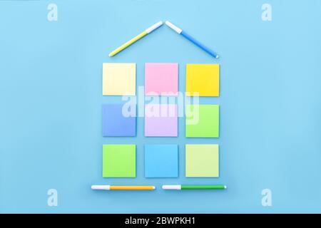 House made of colorful stickers and markers on blue background. Copy space, flat lay. Concept office and back to school. Stock Photo
