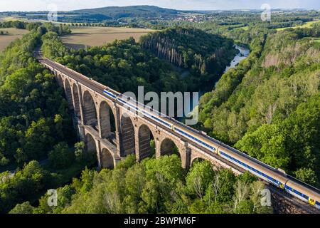 14 September 2017, Saxony, Göhren: A train of the Mitteldeutsche Regiobahn (MRB) crosses the Zwickauer Mulde on the Göhren viaduct. The railway bridge, originally 512 meters long and 68 meters high, is the third largest of these structures in Saxony. For years only regional trains have been running on the only slightly electrified line between Leipzig and Chemnitz. The planned expansion of the line will not begin until 2025 at the earliest. If conditions are favourable, the line could be double-tracked and electric power could be available three years later. (Aerial photograph with drone) Phot Stock Photo