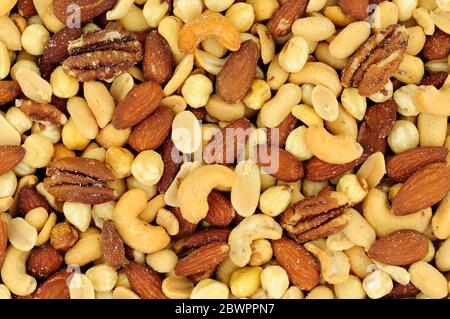 Roasted salted mixed nuts flavourful snacking background Stock Photo