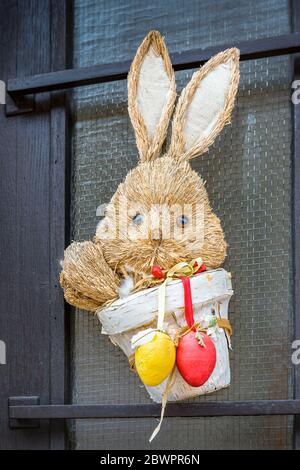 Decorative easter decoration on the door. In the pot with Easter eggs sits a rabbit. Stock Photo