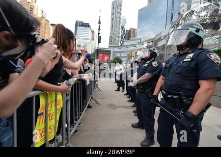 New York City, USA. 02nd June, 2020. A woman makes a hand gesture at NYPD officers in riot gear as protestors make a stop in front of Trump Towers on Manhattan's West Side, during a march over the death of George Floyd, New York, NY, June 2, 2020. New York City changed the imposed an 11 p.m. curfew to 8 p.m. due to continued rioting and looting of stores during protests over George Floyd's death at the hands of Minneapolis police on May 25th. (Anthony Behar/Sipa USA) Credit: Sipa USA/Ģ����ý Live News Stock Photo