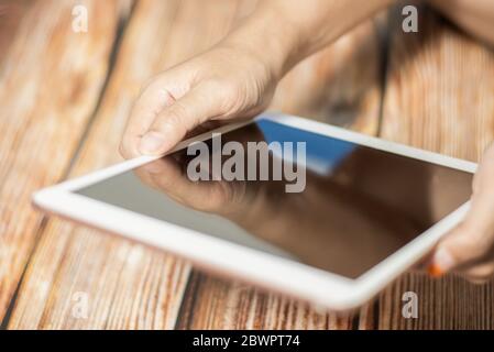 Female hand using  modern digital tablet similar to ipad . Concept of modern gadgets in use. Close-up image with blurred depth of field. Stock Photo