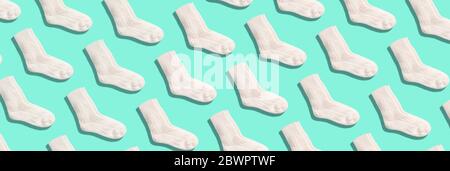 Pair of white woolen knitted socks pattern on blue background. Top view. Copy space. Creative design for packaging. Christmas and New Year cozy holida Stock Photo