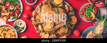 New year dinner table. Roasted Christmas chicken with orange slices, cranberries, garlic, festive decoration, candles, tangerine, pomegranate, golden Stock Photo