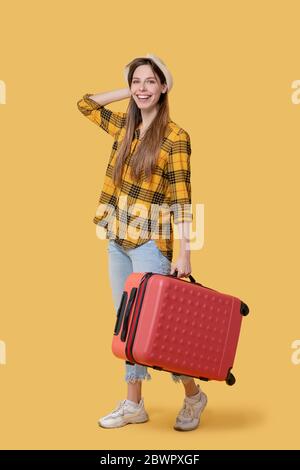 Young adult girl in a plaid shirt with a red suitcase. Stock Photo