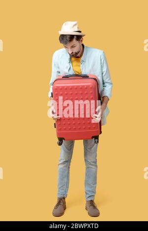 Sad man clutching a suitcase looking down Stock Photo