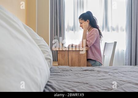 Side view of focused young woman sitting at home and working on laptop. Caucasian woman working from home office.  Photo with selective focus Stock Photo