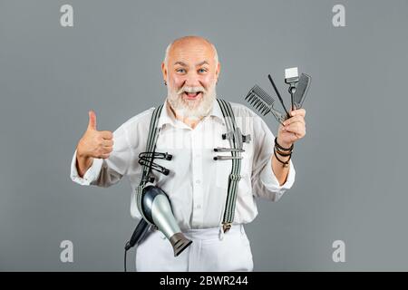 Attractive barber with scissors at barber shop. Professional hairdresser in ctudio on gray background. Barber tools. Stock Photo