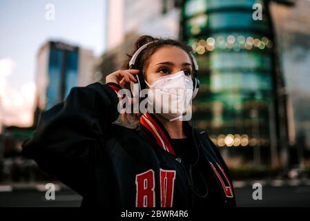 young girl dressed in sport wears medical mask on city street in spain. Coronavirus pandemic Covid-19 Stock Photo