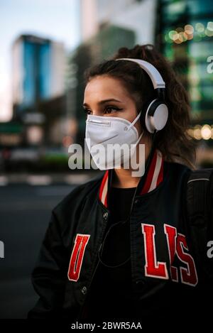 young girl dressed in sport wears medical mask on city street in spain. Coronavirus pandemic Covid-19 Stock Photo