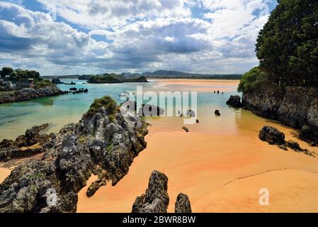 Rock formations and clean wet sand at beautiful beach during low tide Stock Photo