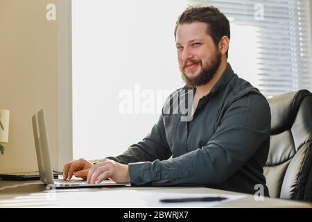 Male manager sitting at office desk working on laptop computer. Stock Photo