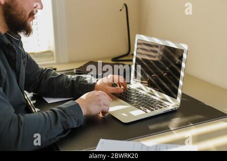 Male programmer writing program at office on laptop, typing on keyboard. Stock Photo