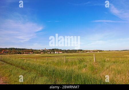 A view across the marshes from Beach Road on the North Norfolk coast to the village of Salthouse, Norfolk, England, United Kingdom, Europe. Stock Photo