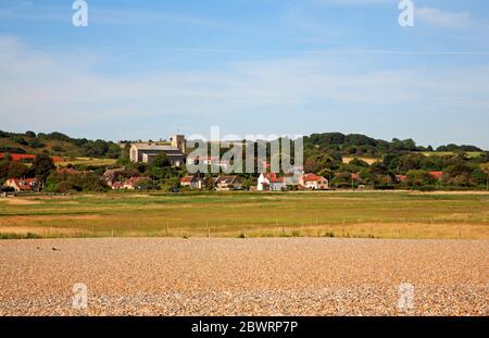A view of the village and church from the shingle ridge across the marshes in North Norfolk at Salthouse, Norfolk, England, United Kingdom, Europe. Stock Photo