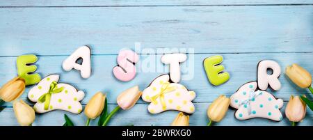 Sweets for celebrate Easter. Gingerbread in shape of easter bunny and letter Easter. Blue background top view copy space Stock Photo