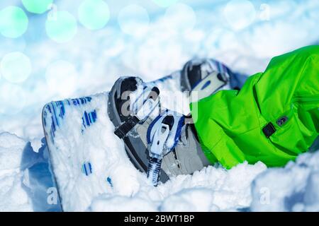 Close-up of a small snowboard in snow attached to child legs with lens flares on background Stock Photo