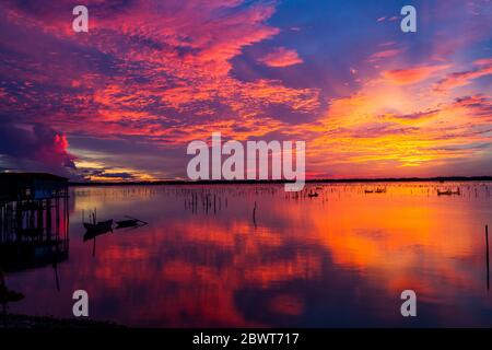 Wonderful landscape at Lap An lagoon, Vietnam with the floating house, wooden boat and amazing colorful sky of sunrise. Stock Photo