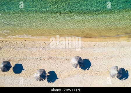 Adriatic sea shore in Croatia on Pag island, beautiful sand beach with parasols, overhead view from drone