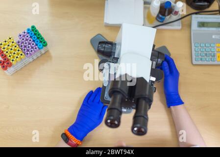 Scientist conducting research taking notes whilst looking through microscope selective focus laboratory assistant is looking through a microscope. Clo Stock Photo