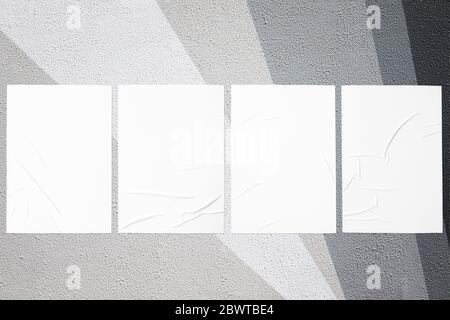 Closeup of geometrical gray painted urban wall texture with four wrinkled glued poster templates. Modern mockup for design presentation with clipping Stock Photo