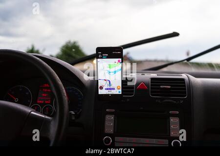 Using waze maps application on smartphone on car dashboard, Driver using maps app for showing the right route through the traffic of city at sunset on Stock Photo