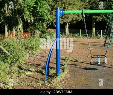 Colourful blue and green childrens swing in unused park during lockdown Stock Photo