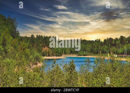 A lake with crystal clear water. The concept of rest by the lake, rest by the reservoir. Beautiful lake among trees, forest. Stock Photo