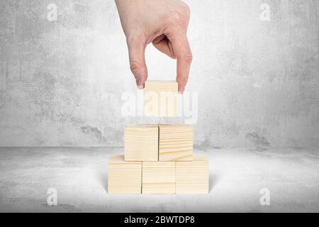 Stacking wooden blocks without content. Business concept, content supplementation. A man arranges blank wooden blocks one on top of the other, creatin Stock Photo