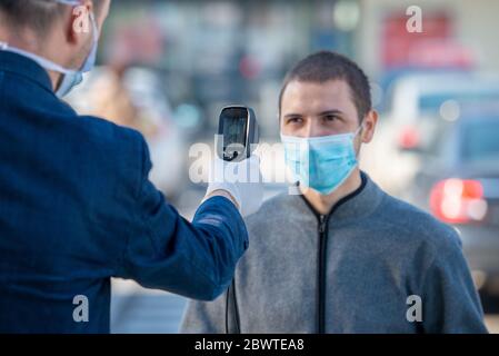 Temperature check at a supermarket of man, grocery store with thermal imaging camera. Image monitoring scanner to monitor the body temp of visitor cus Stock Photo