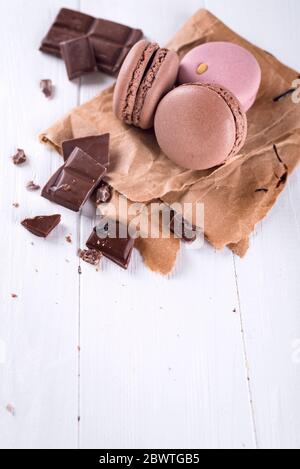 Chocolate french macaroons with chocolate pieces on white background with space under the text Stock Photo