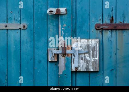 latch and padlock on old wooden door with weathered turqoise paint Stock Photo