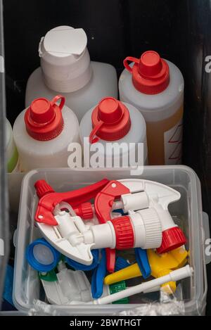 A top down view of a bucket with various colorful cleaning supplies and spray bottle tops and pumps Stock Photo