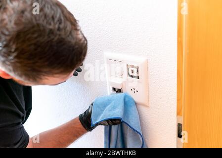 A close up of a professional cleaner cleaning a modern light switch and dimmer and socket with a micro fiber cloth Stock Photo