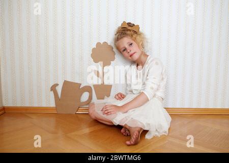 Portrait of girl playing with cardboard watering can and flower Stock Photo