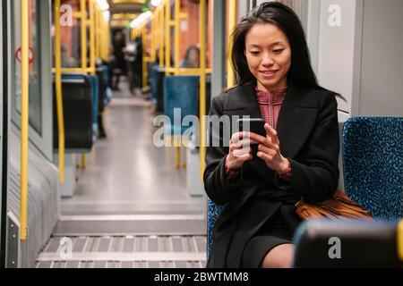 Young woman using smartphone in a metro Stock Photo
