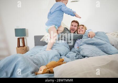 Family relaxing and jumping on bed Stock Photo