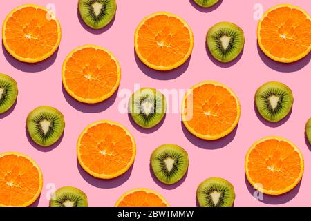 Pattern of orange and kiwi fruit slices against pink background Stock Photo