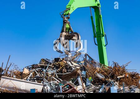 Germany, Baden-Wurttemberg, Stuttgart, Mechanical claw over heap of scrap metal lying in junkyard Stock Photo