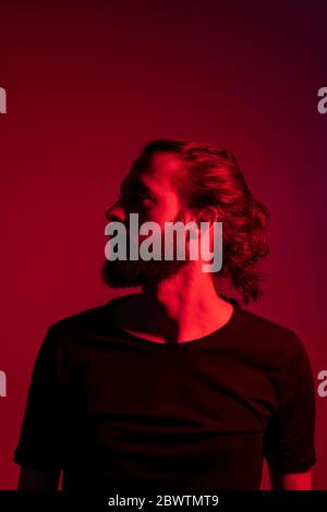 Portrait of red illuminated young man  against red background Stock Photo