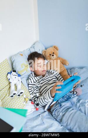 Boy lying in bed using digital tablet Stock Photo