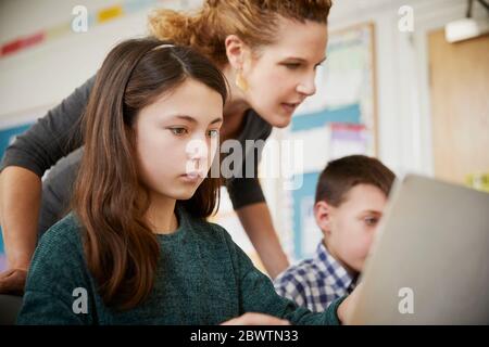 Girl and boy in a classroom during a lesson on laptops with a teacher Stock Photo