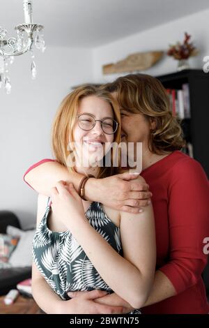 Mother hugging her adult daughter at home Stock Photo