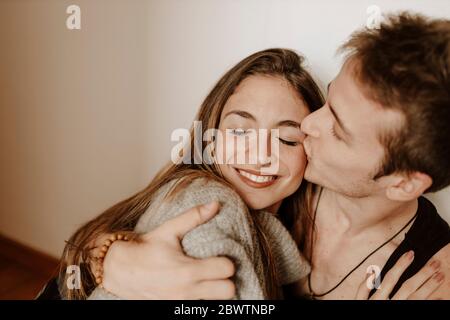 Happy young couple hugging and kissing at home Stock Photo