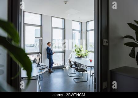 Businessman standing at thw window in office Stock Photo