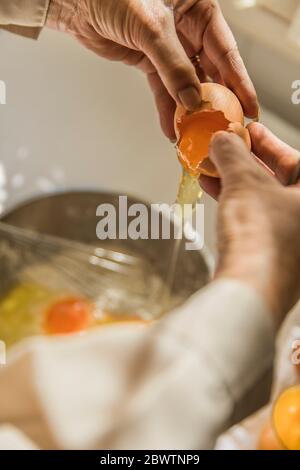 Hands of woman cracking egg into bowl Stock Photo